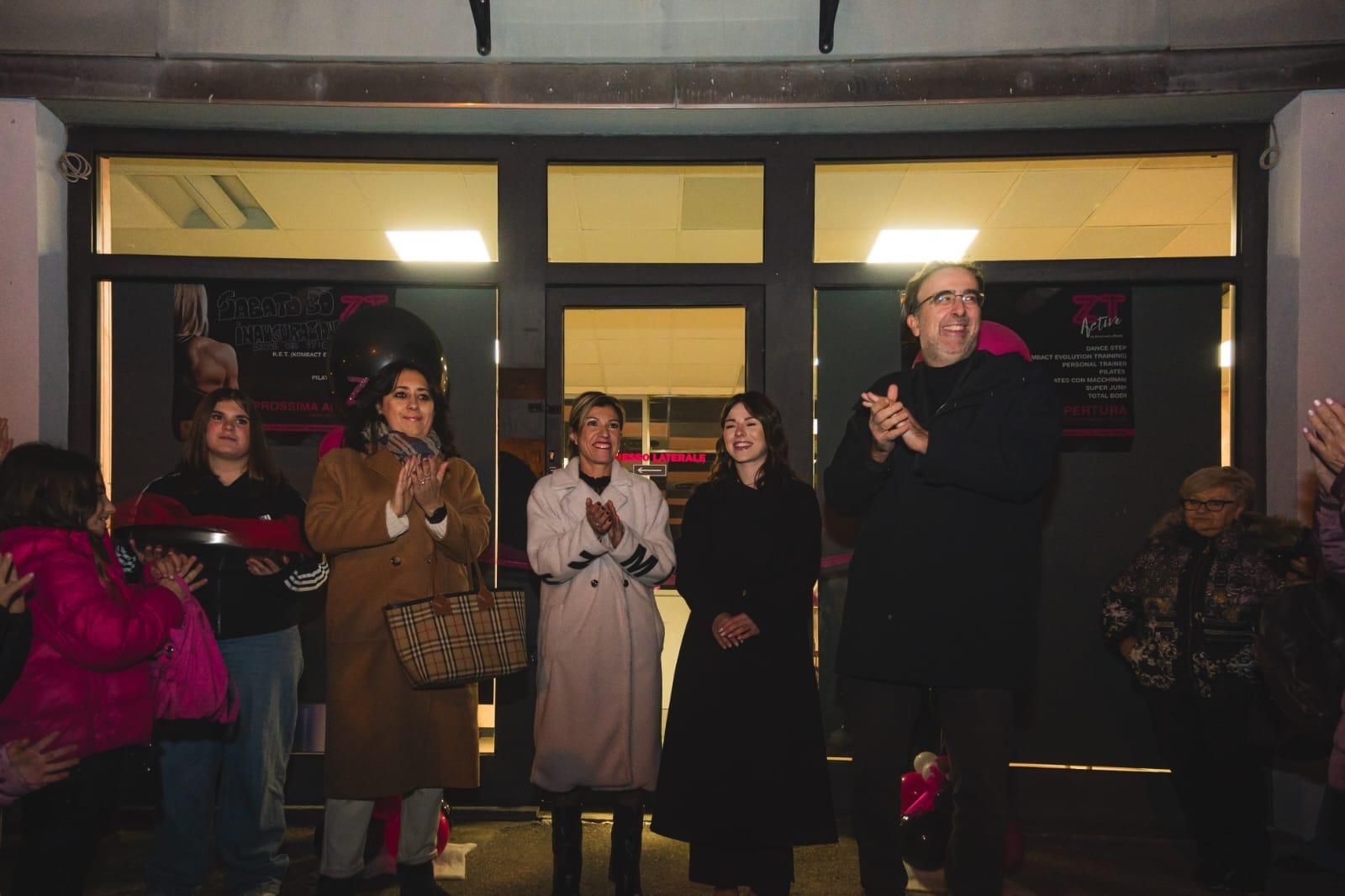 Un gruppo di persone è in piedi davanti a un edificio e applaude.