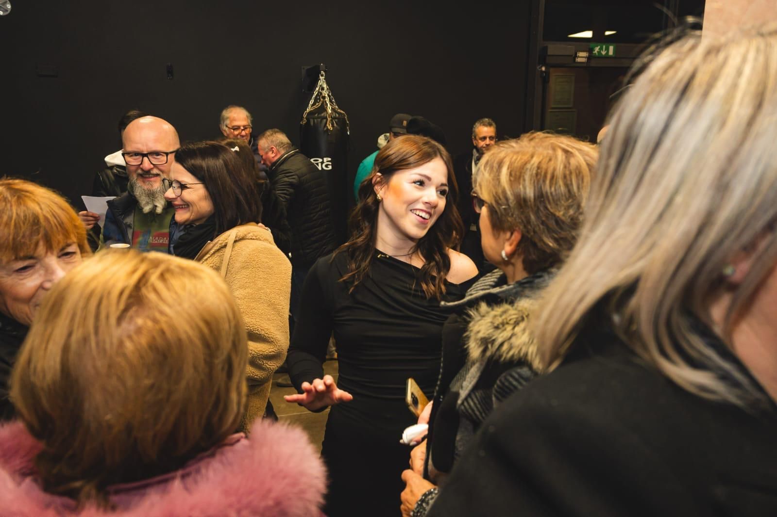 Un gruppo di donne è in piedi in una stanza e parla tra loro.