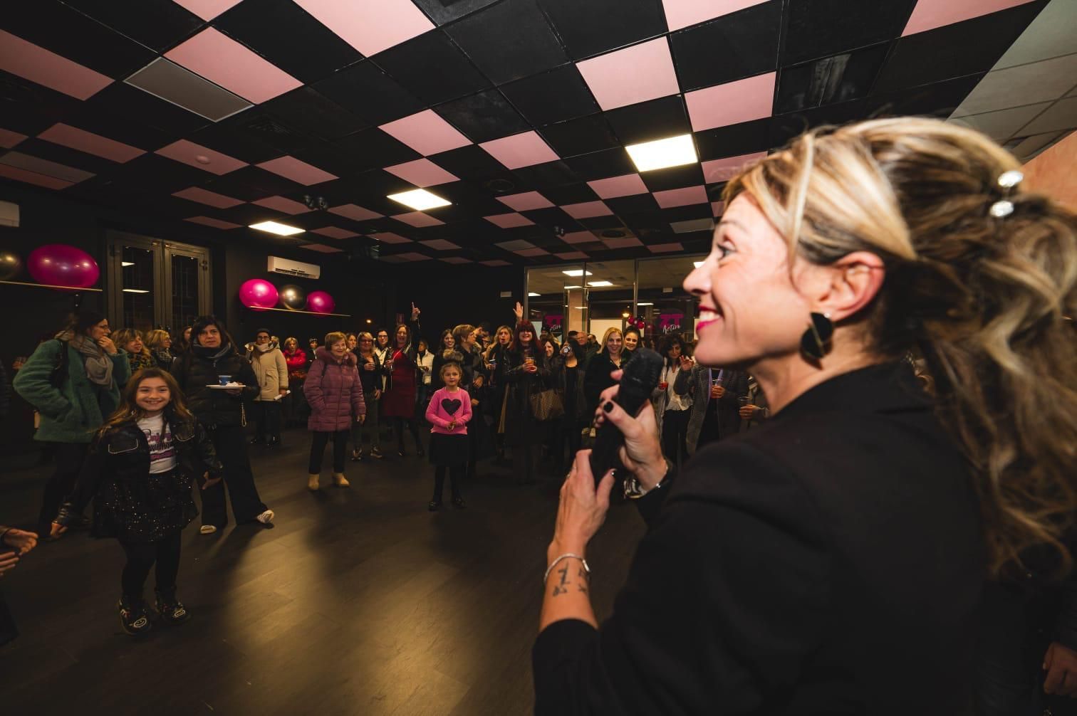 Una donna tiene in mano un microfono di fronte a una folla di persone.