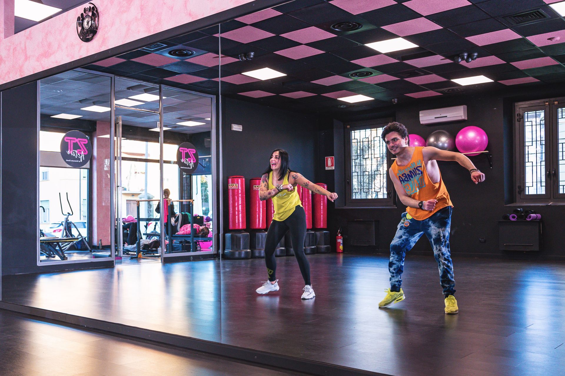 Un uomo e una donna ballano davanti a un grande specchio in una palestra.