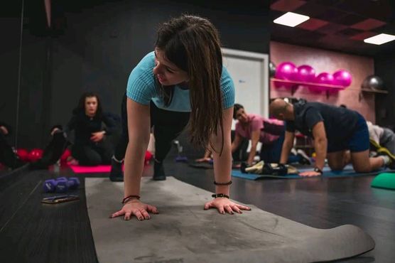 Un gruppo di persone sta facendo flessioni su un tappetino da yoga in una palestra.
