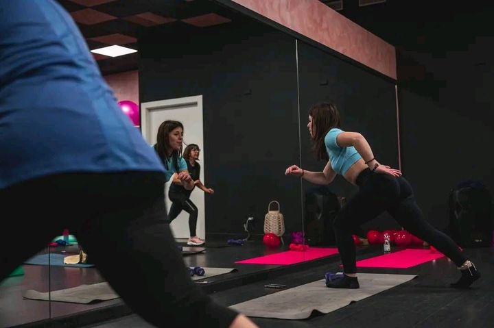 Una donna fa yoga davanti allo specchio in una palestra.