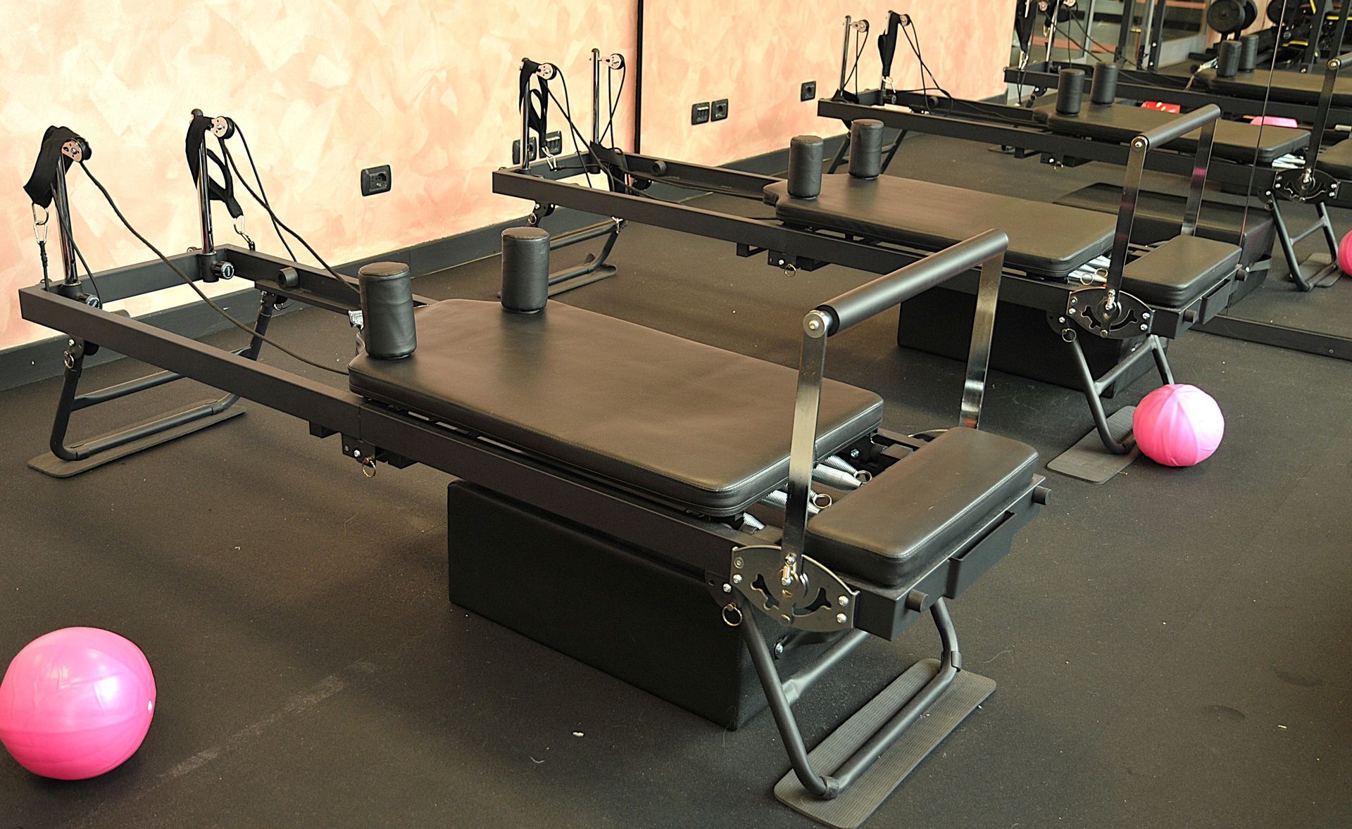 Una fila di tavoli da pilates con palline rosa sul pavimento