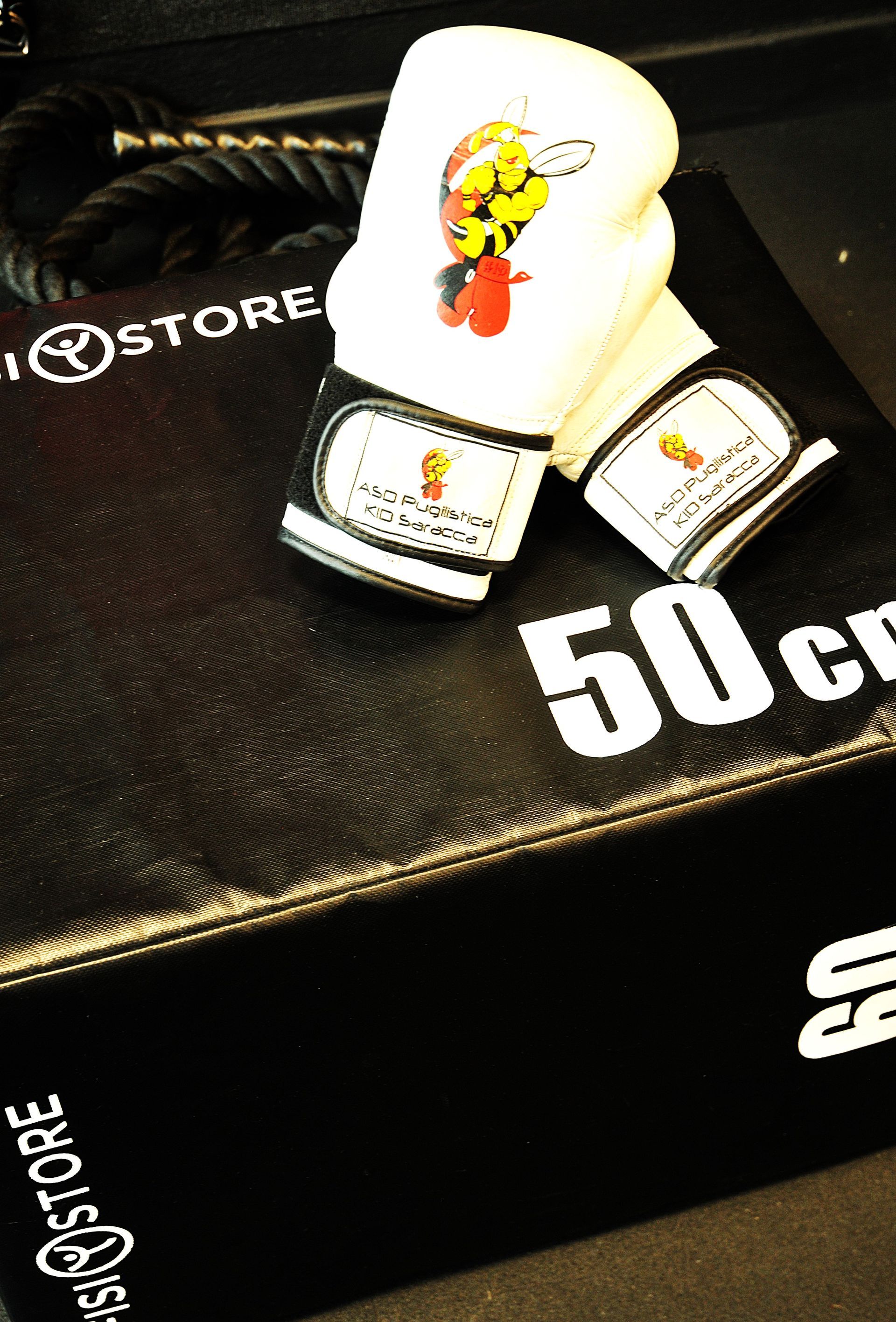 Un paio di guantoni da boxe appoggiati su una scatola con la scritta 50 cm