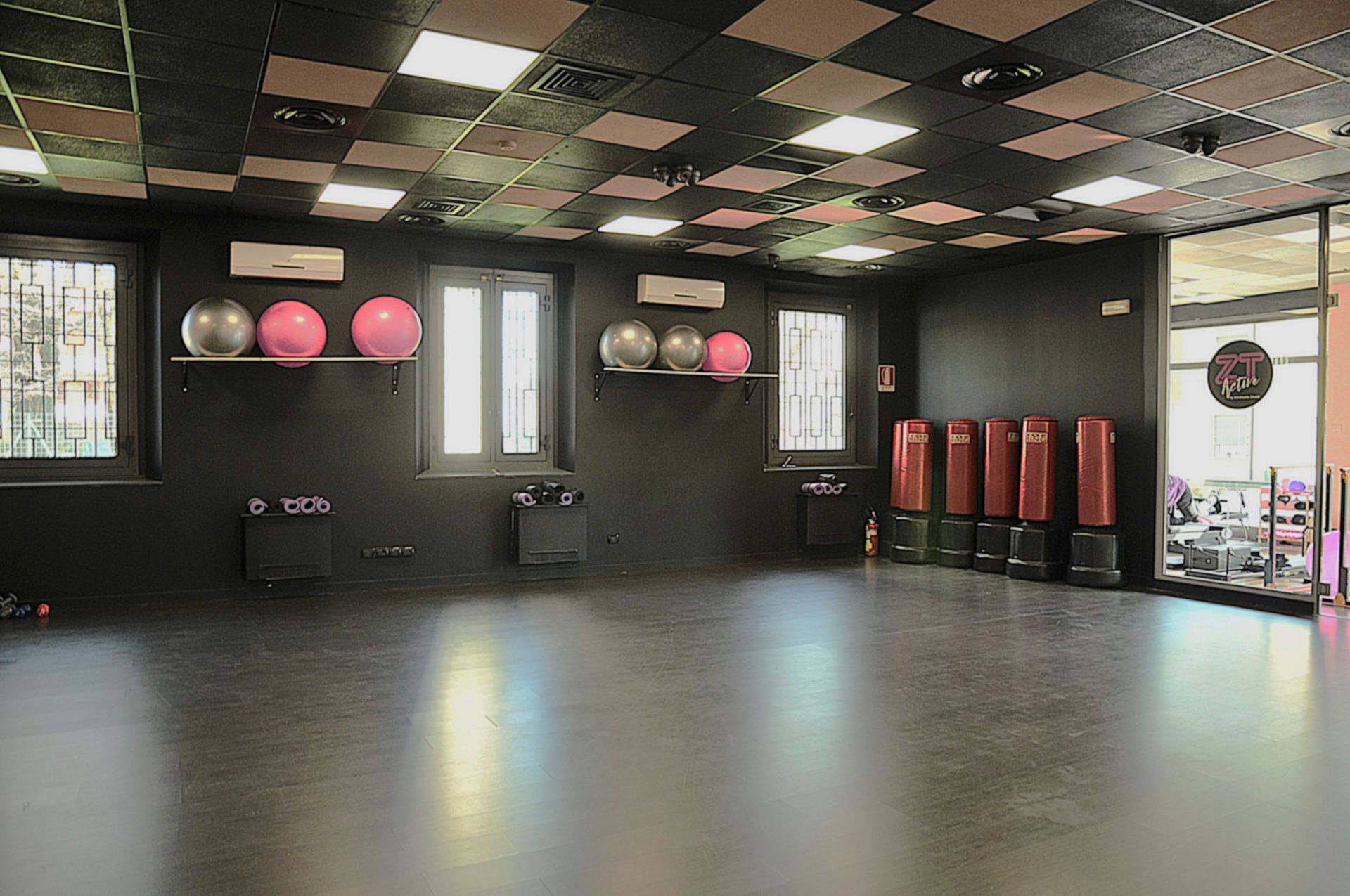 Una grande palestra vuota con un sacco di palle da ginnastica sul muro.