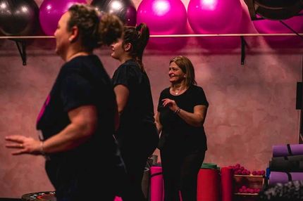 Un gruppo di donne è in piedi una accanto all'altra in una palestra.