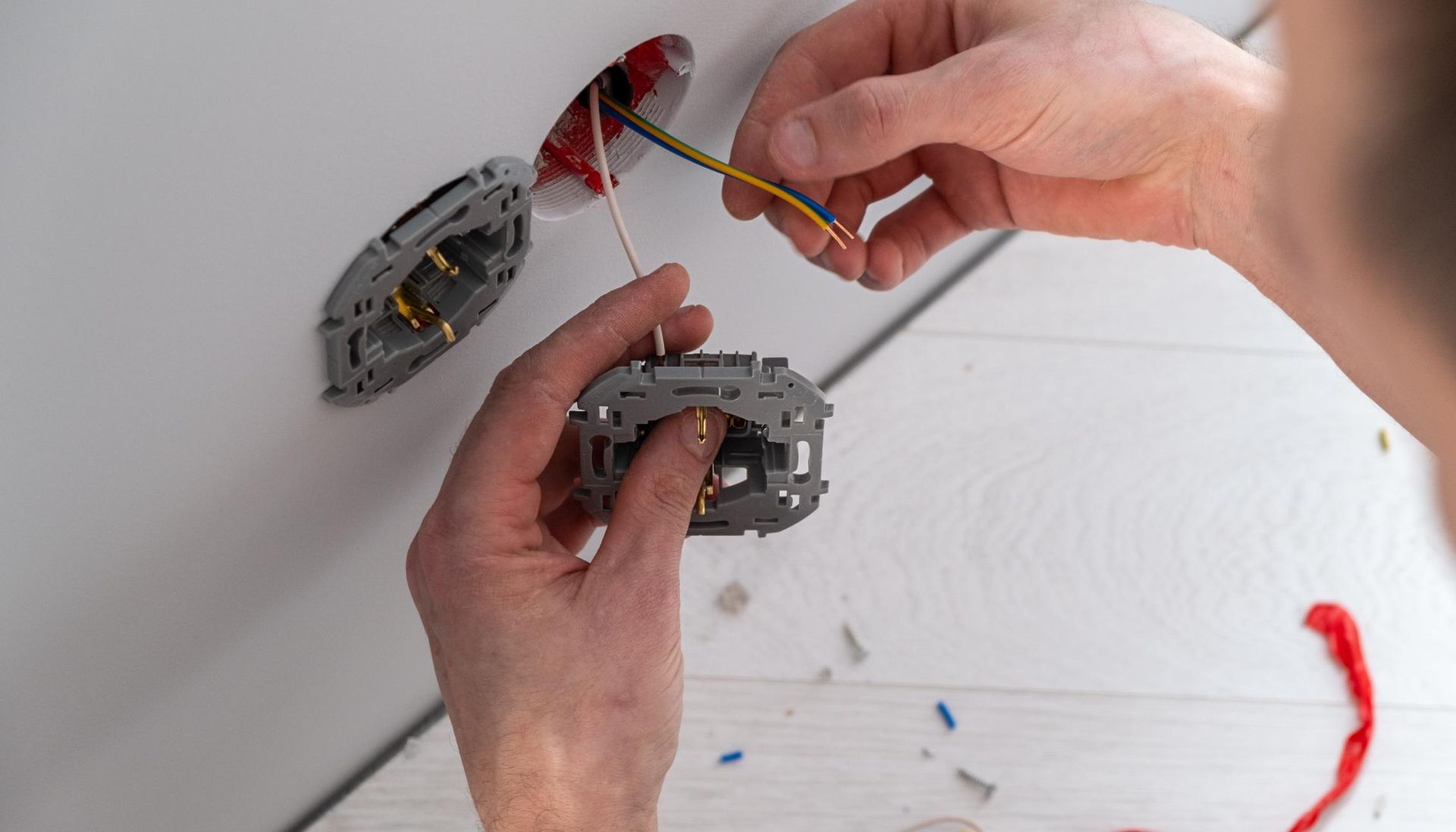 A person is installing a light switch in a wall.