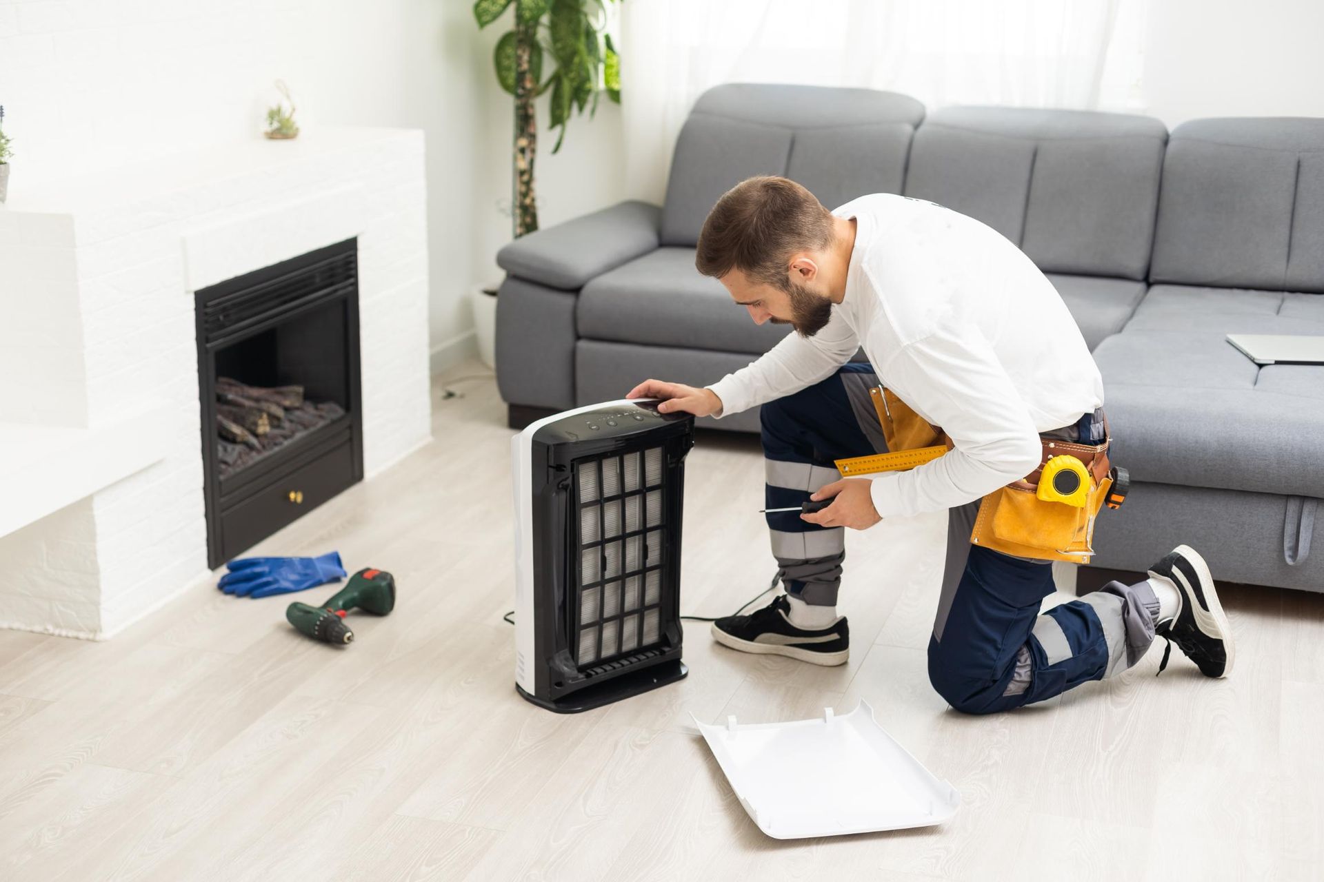 A man is repairing an air purifier in a living room.