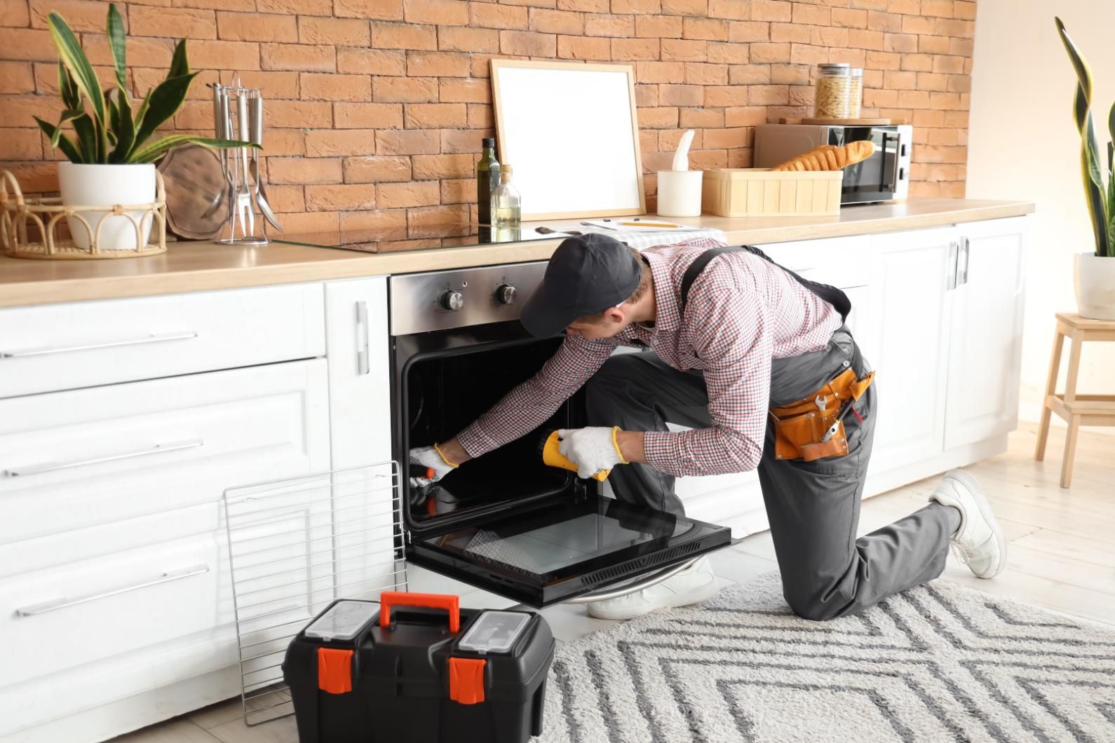 A man is fixing an oven in a kitchen.