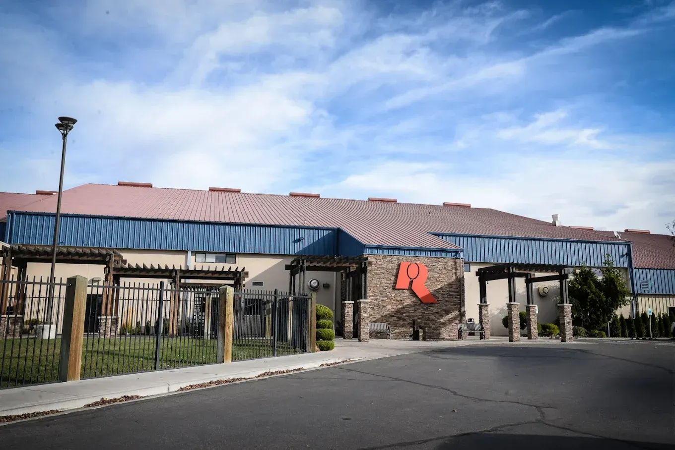 Building exterior with a red roof and large red initials, under a blue sky.