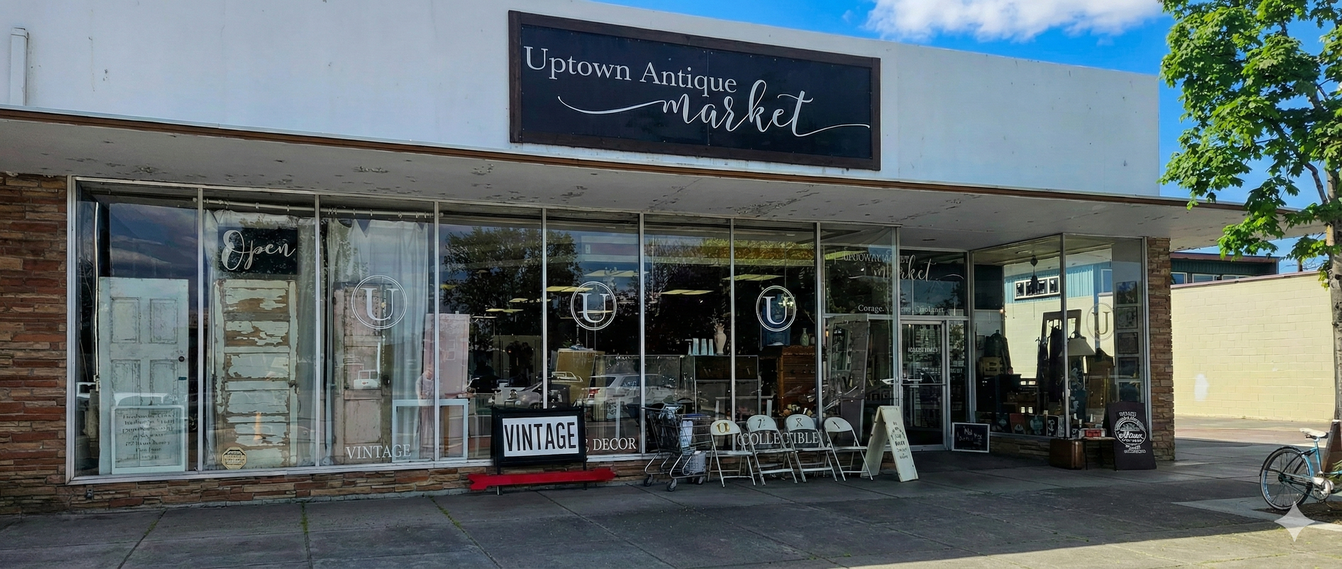 Storefront of a vintage market with glass windows displaying antiques, under a sign that reads 