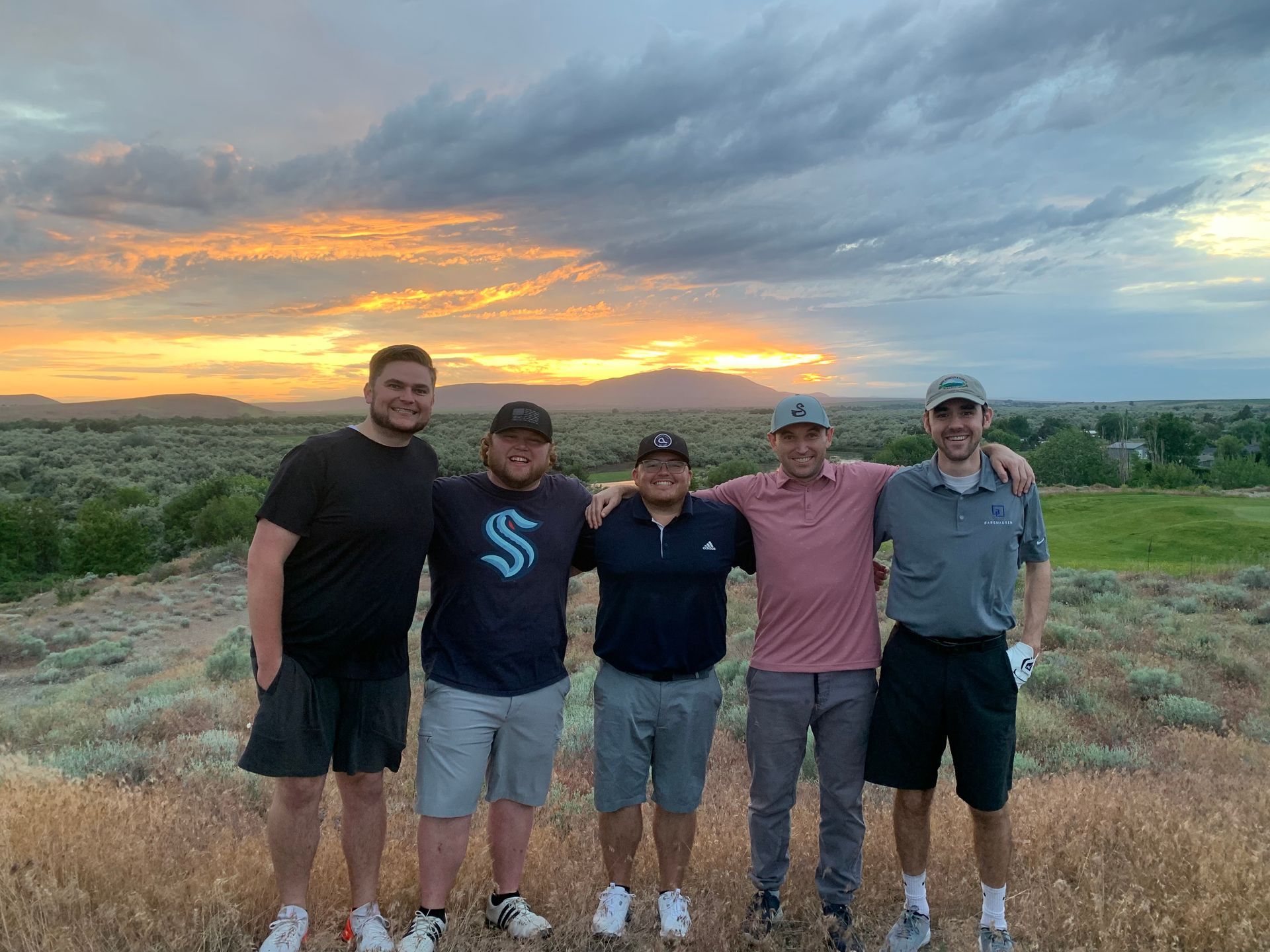 Five men standing together outdoors, arms around each other at sunset at Horn Rapids in Richland, WA.