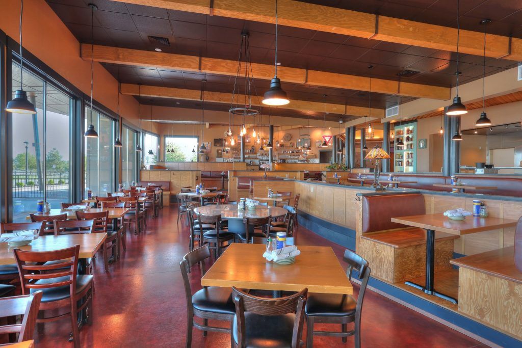 Interior view of a restaurant with tables, chairs, booths, and pendant lights.
