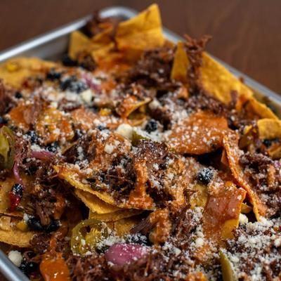 Nachos on a tray, with meat, cheese, black olives, and jalapeños.