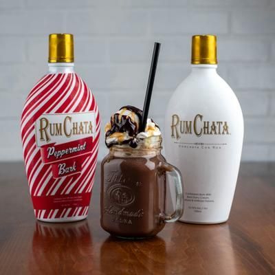 Two RumChata bottles and a chocolate drink in a jar with whipped cream and a straw. One bottle is peppermint bark.