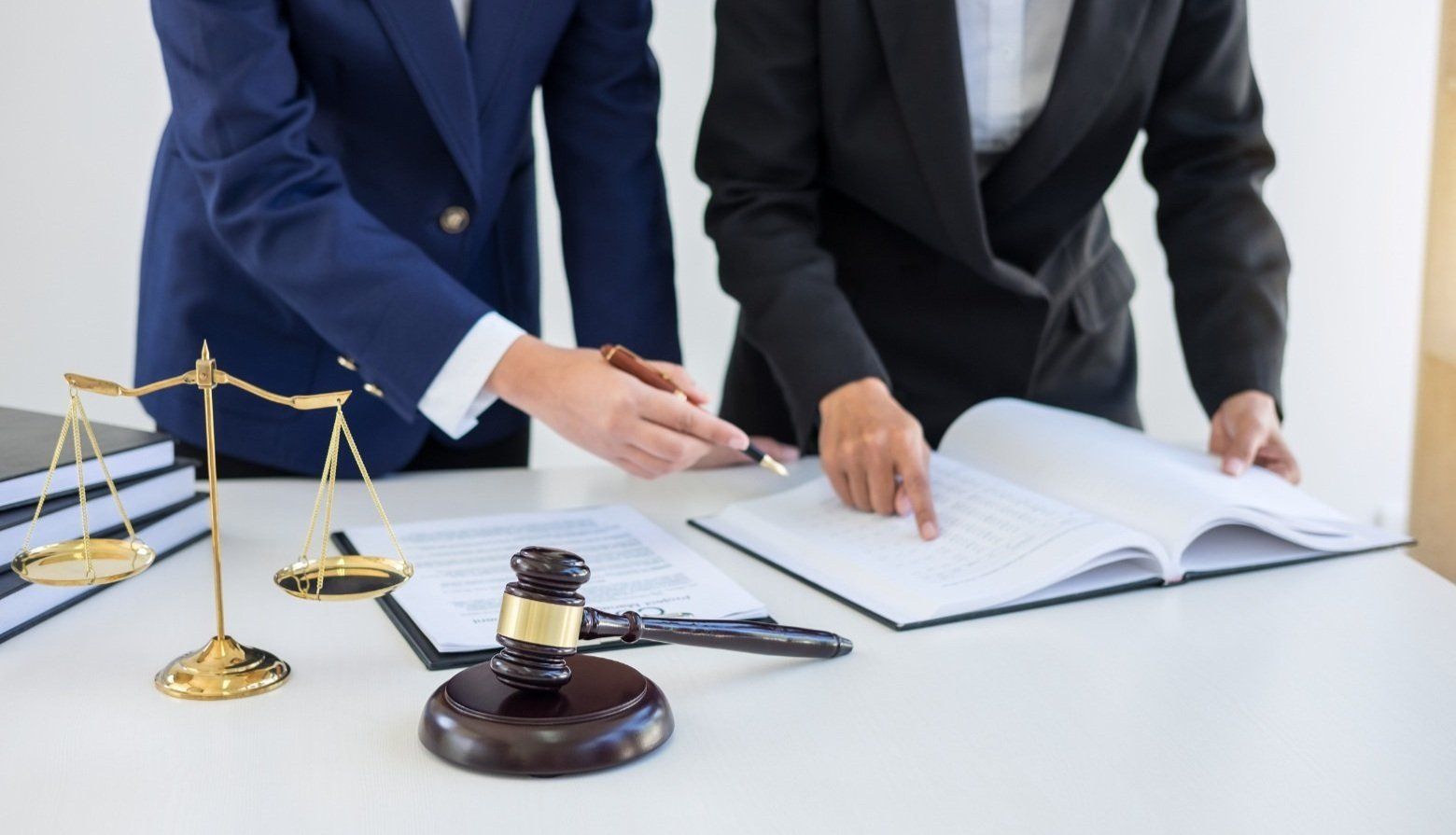 Two lawyers are sitting at a table looking at a book.