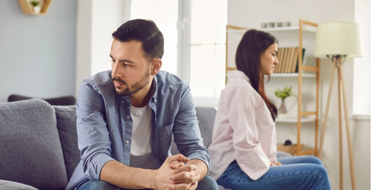 A man and a woman are sitting on a couch having an argument.