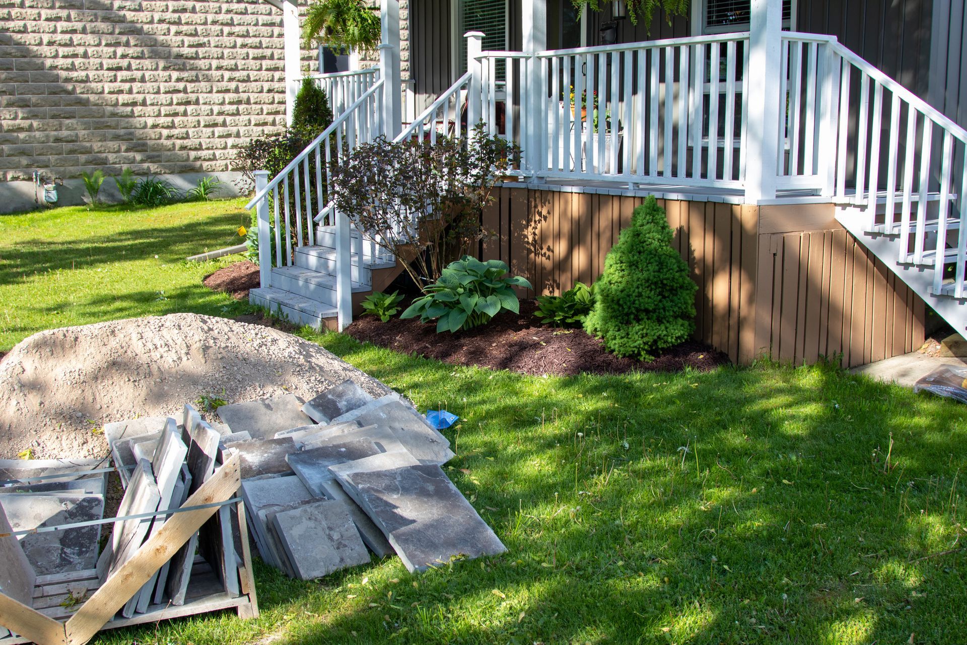 Front porch with landscaping, grass, and construction materials.