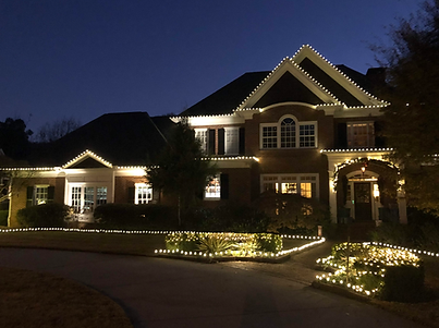 House at night illuminated with white Christmas lights.