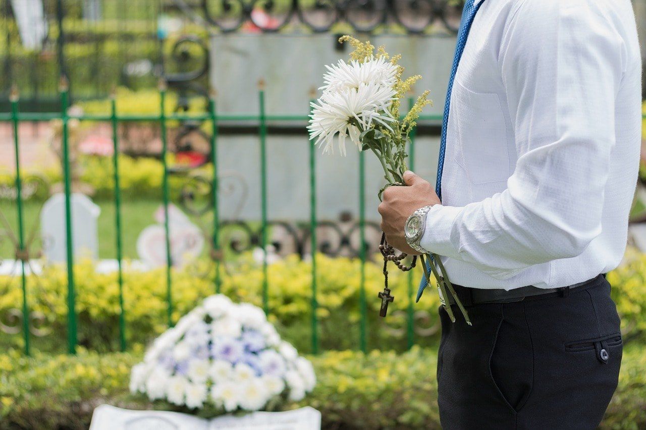 funeral etiquette man holding flowers at gravesite
