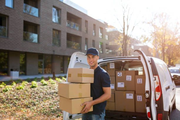 A delivery man is carrying boxes out of a van.