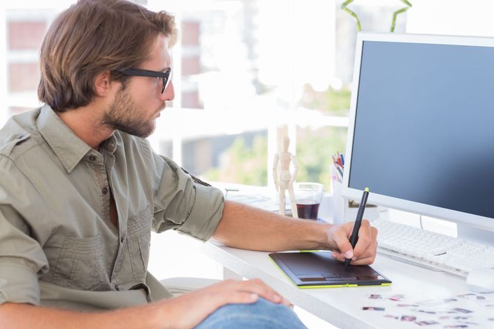 A man is sitting at a desk using a graphic tablet.