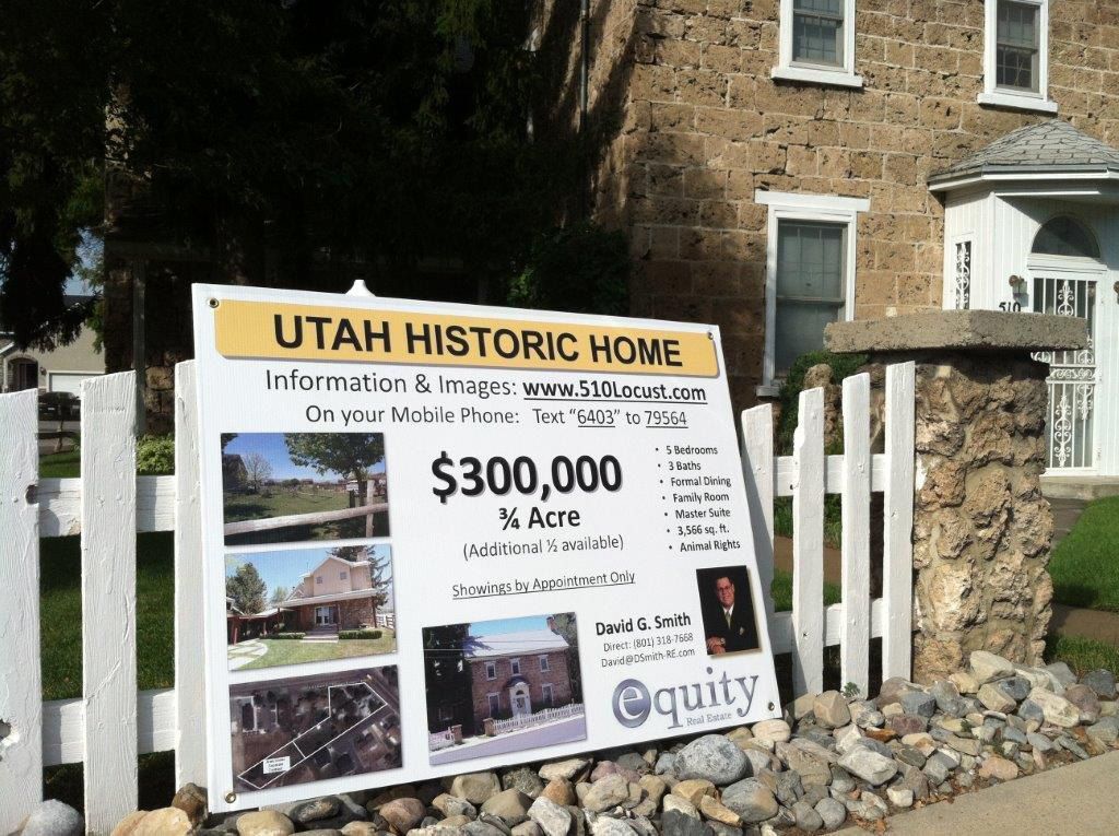 A sign for a historic home is sitting in front of a stone building. A sign for a historic home is sitting in front of a stone building.