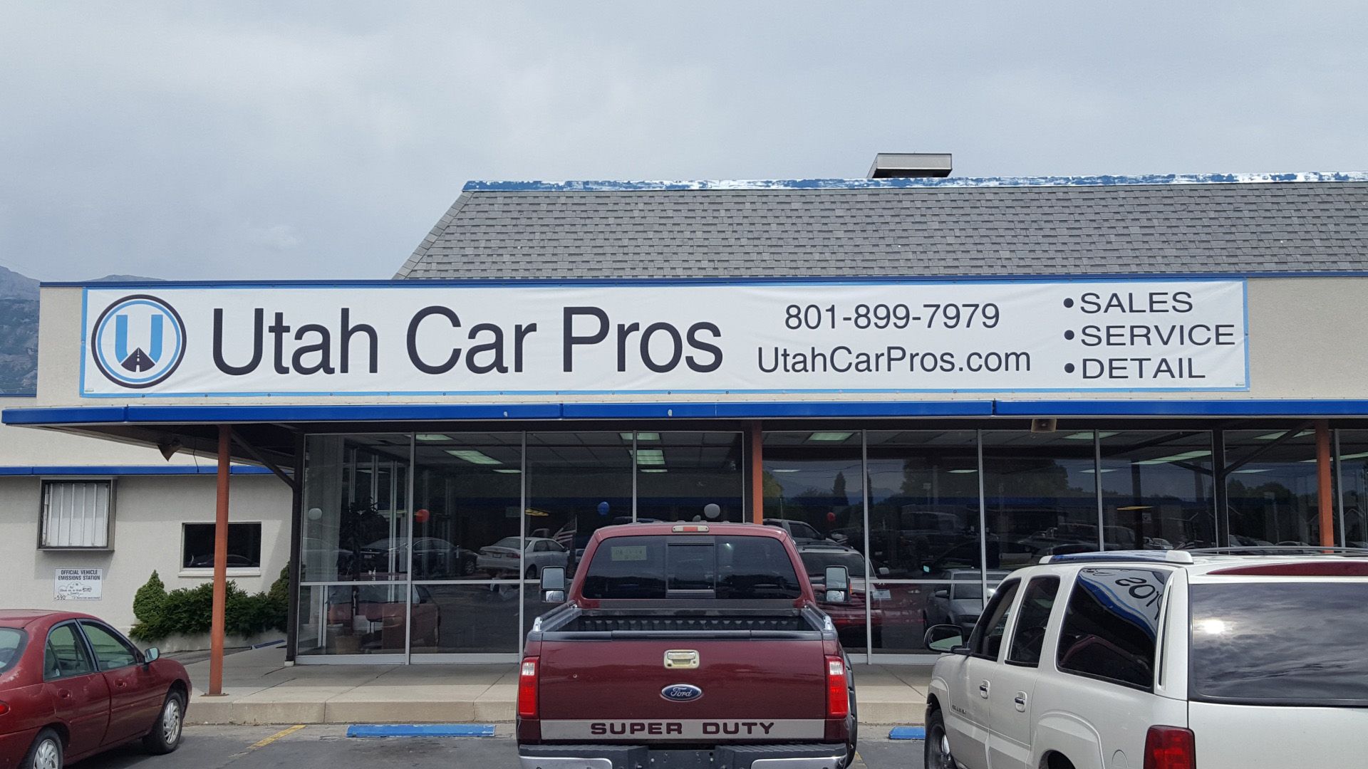 A red truck is parked in front of a utah car pros store A red truck is parked in front of a utah car pros store