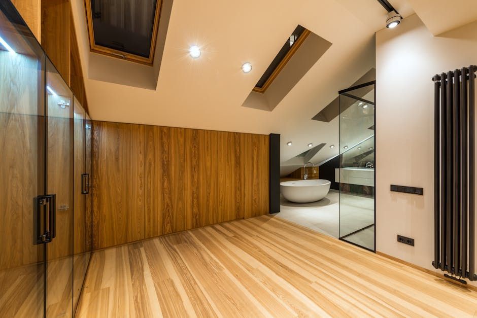 Modern bedroom with wood paneling, skylights, and a glass-enclosed bathroom with a freestanding tub.