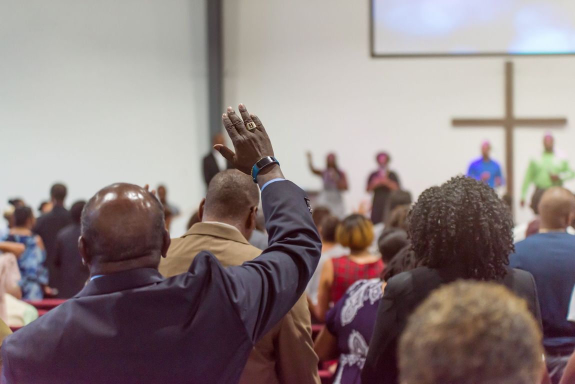 A crowd of people are raising their hands in the air at a worship event.