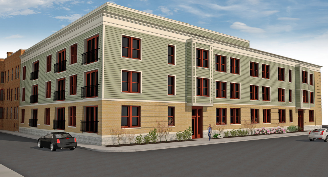 Red brick apartment building under construction with blue window coverings and a snow-covered street in front