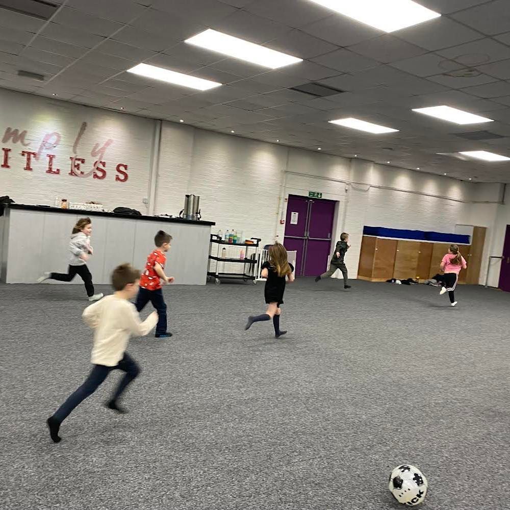a group of children are playing with a soccer ball in a gym .