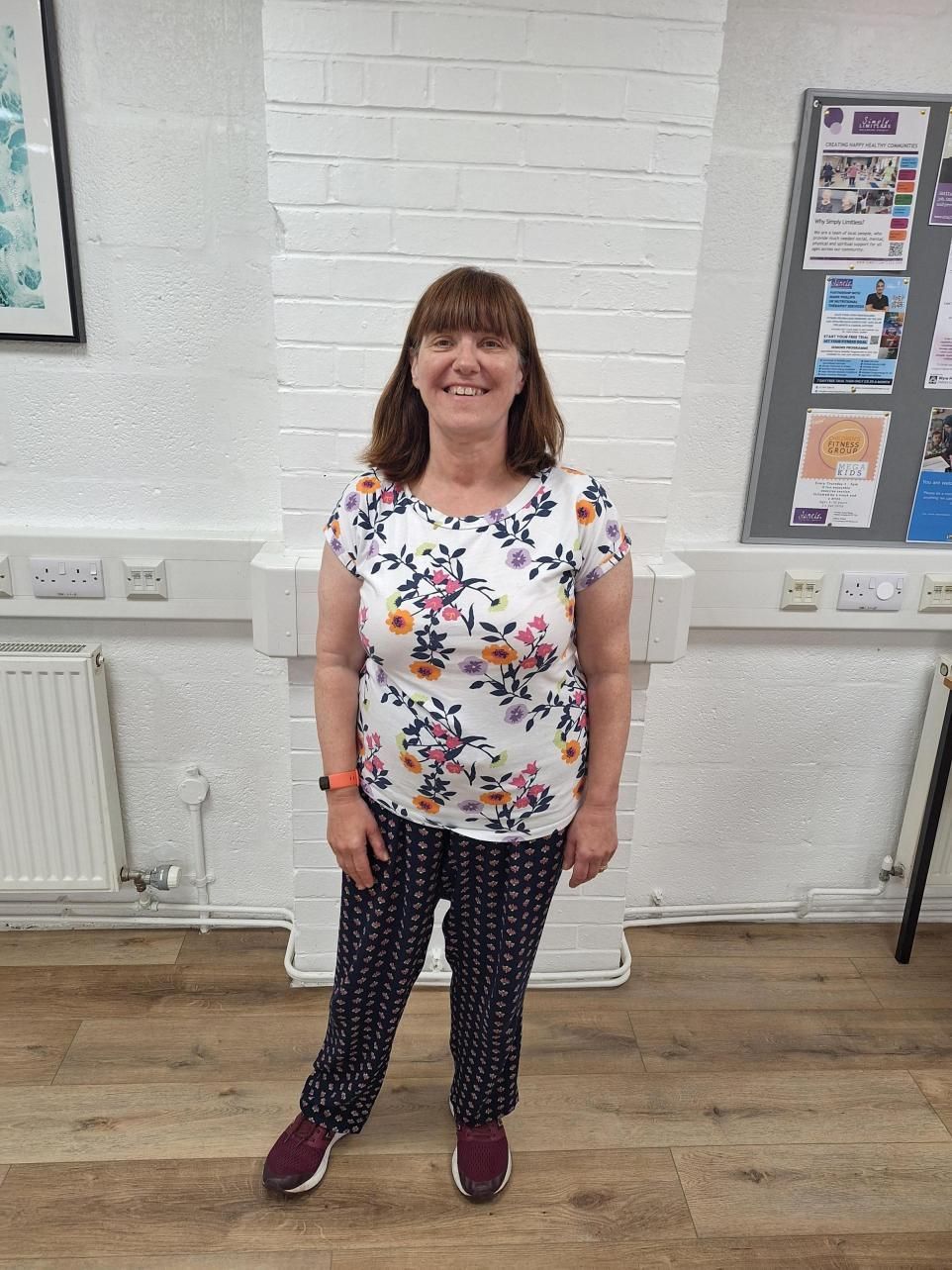 A woman in a floral shirt and pants is standing in a room.