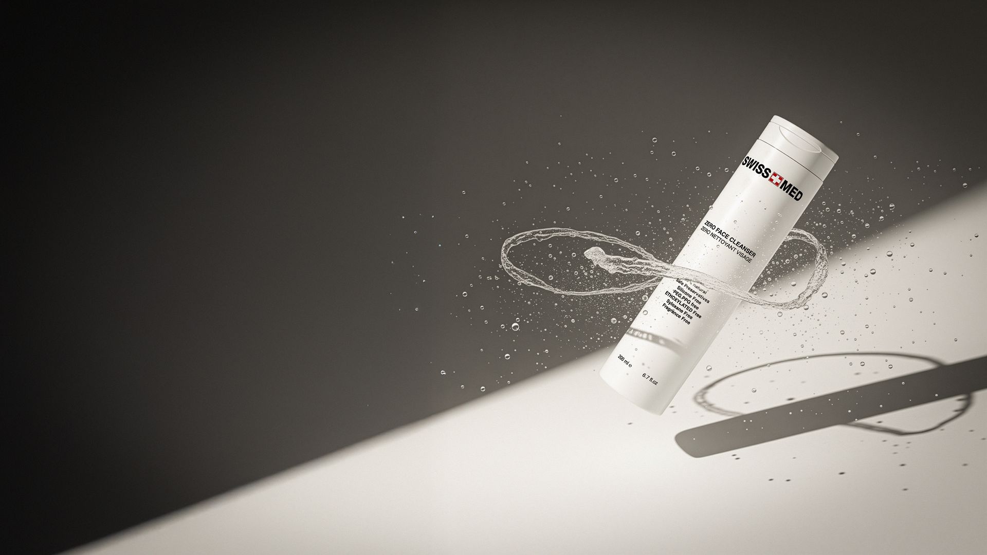 White cylindrical product in mid-air, surrounded by scattering particles, against a two-tone grayscale backdrop.