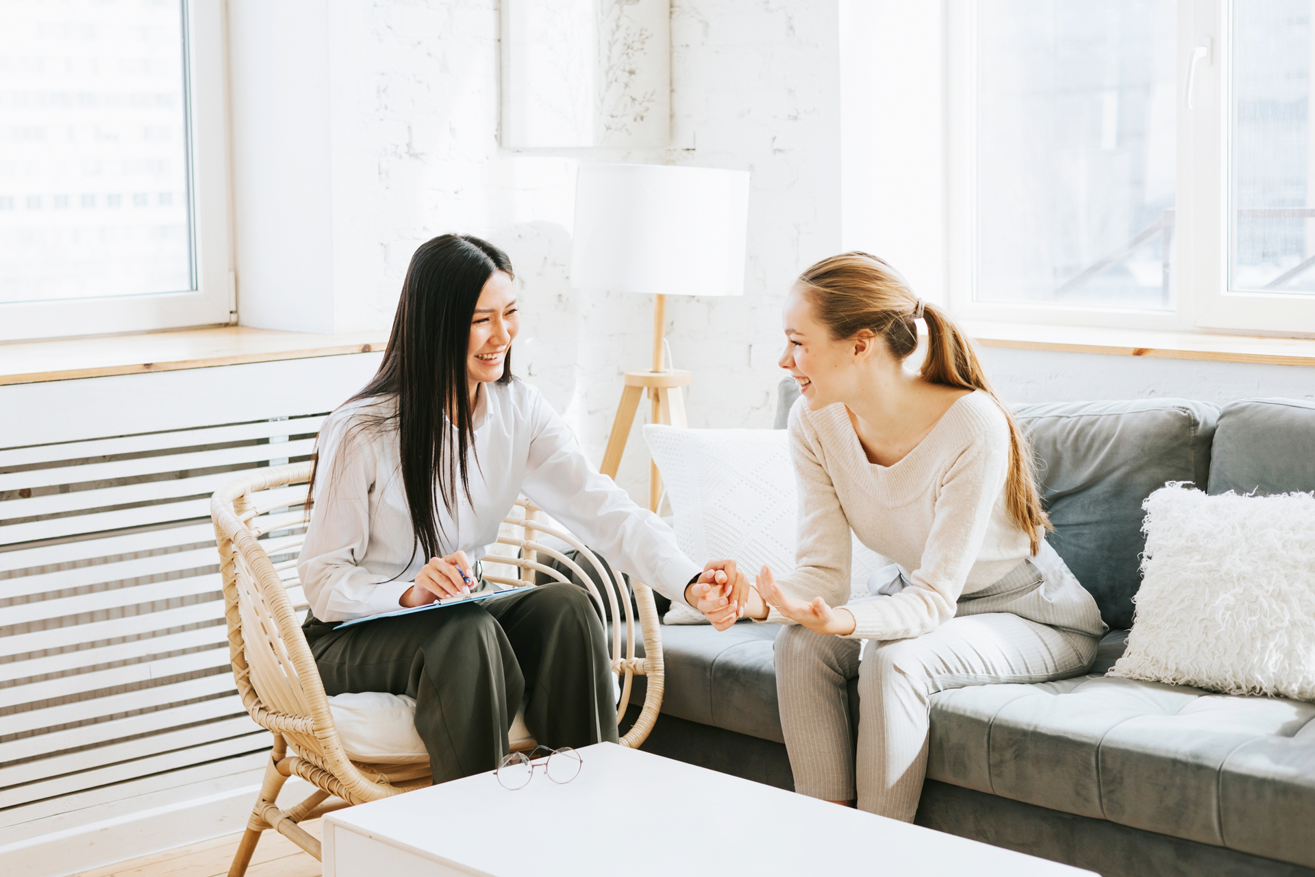 Two women are sitting on a couch talking to each other.