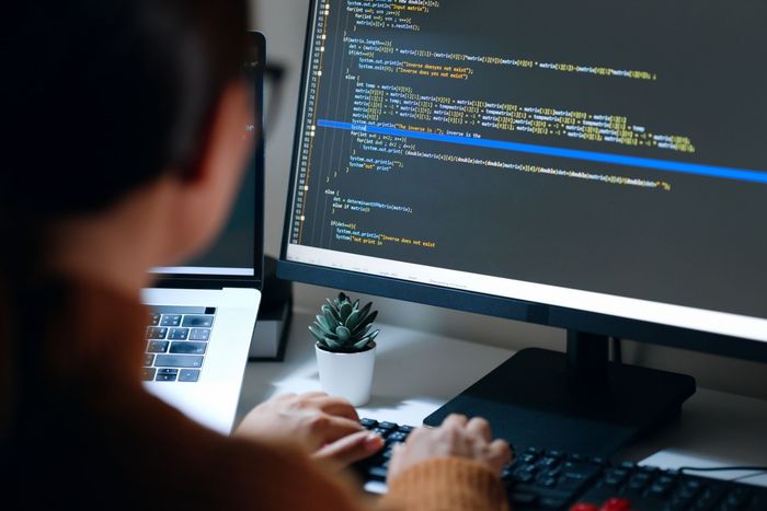 A person is typing on a keyboard in front of a computer monitor.