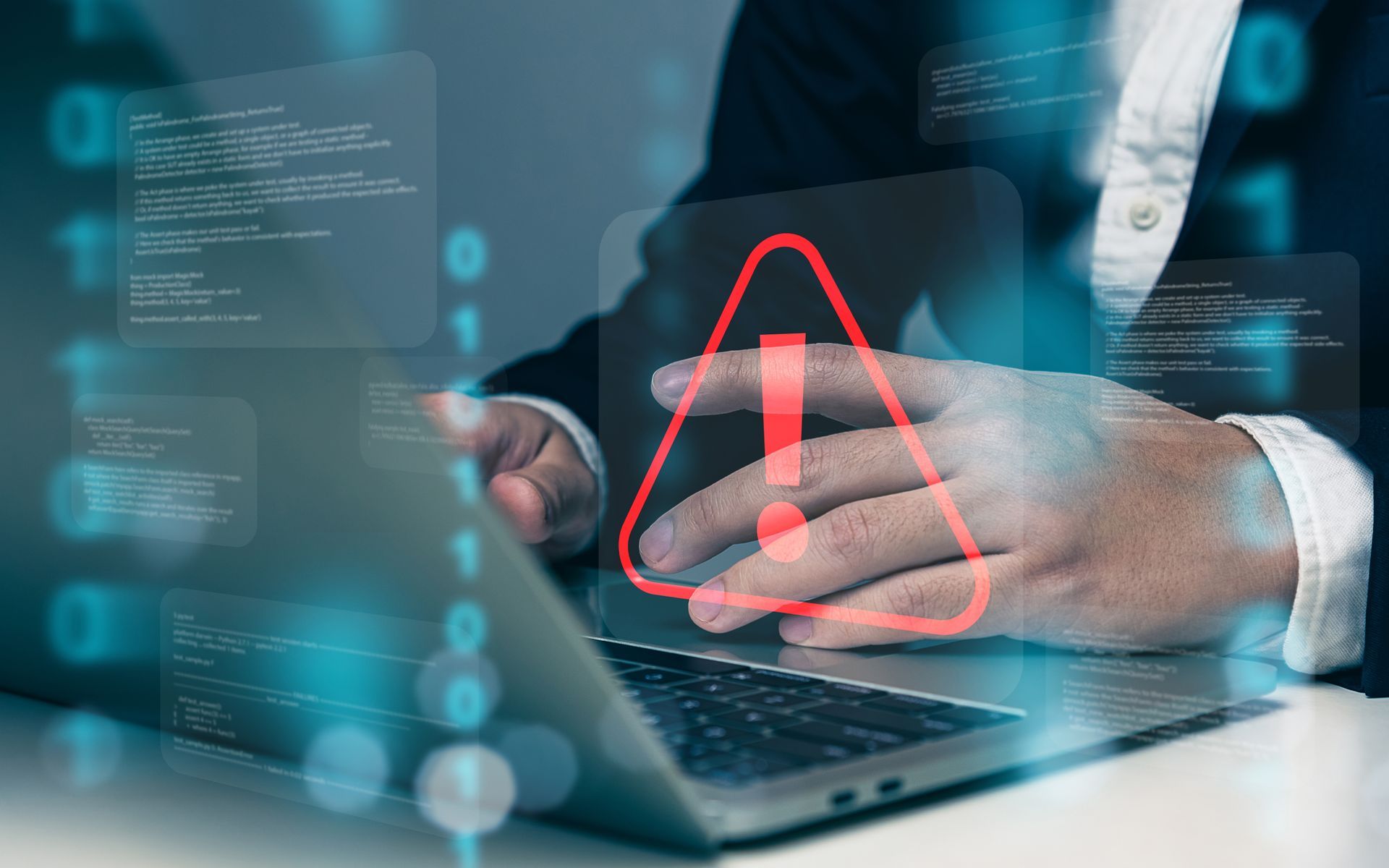 A man is using a laptop computer with a red exclamation point on the screen.