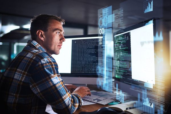 A man is sitting at a desk looking at a computer screen.