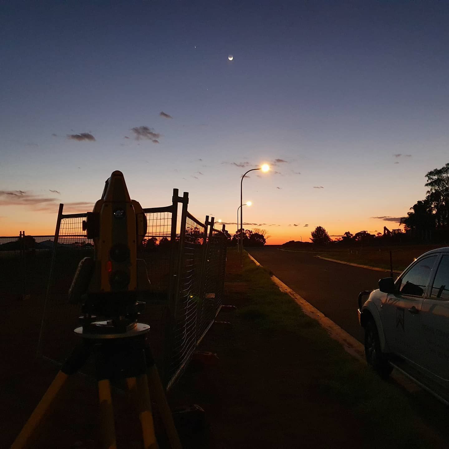 A Person Is Standing On A Tripod In The Middle Of A Road At Sunset — Western Survey Pty Ltd In Dubbo, NSW