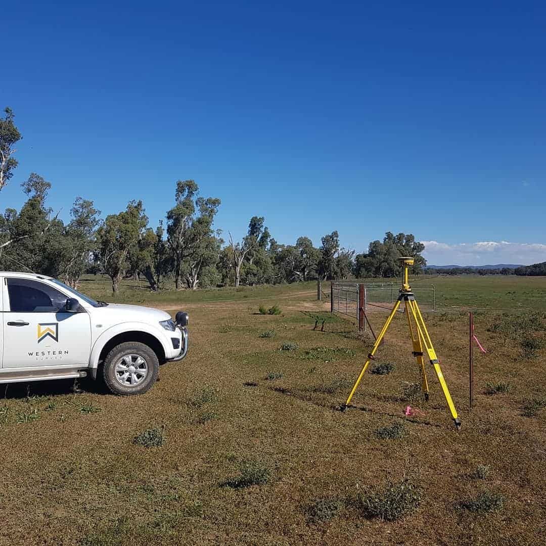 A White Truck Is Parked In A Grassy Field Next To A Yellow Tripod — Western Survey Pty Ltd In Dubbo, NSW
