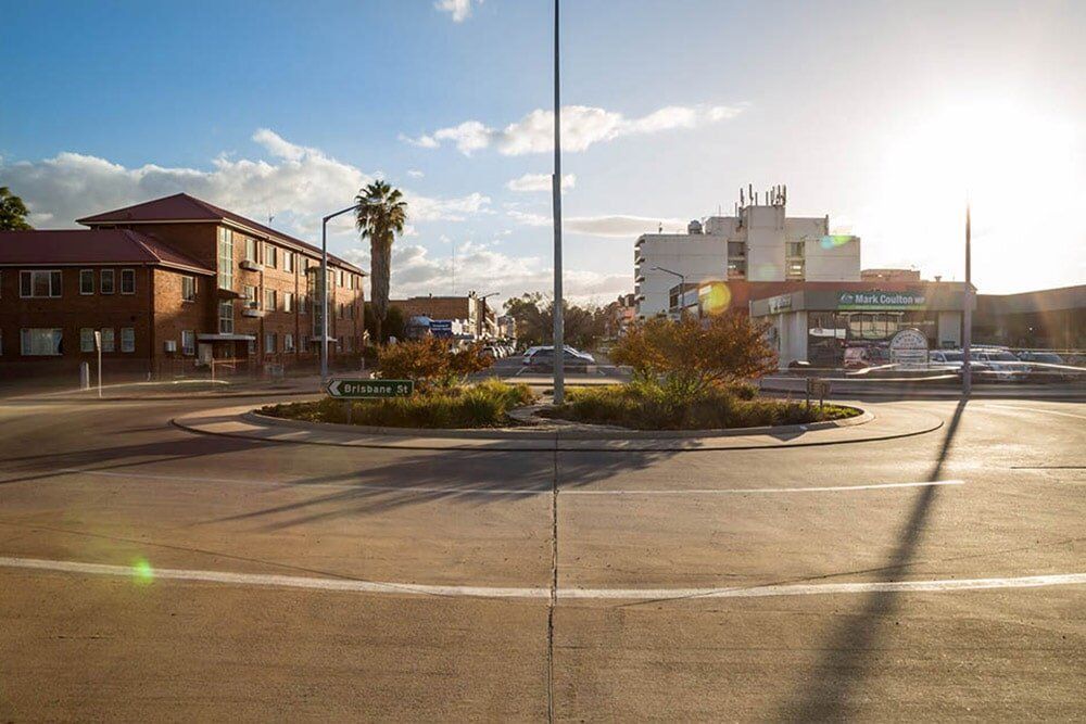 A Parking Lot With A Building In The Background And The Sun Shining Through The Clouds — Western Survey Pty Ltd In Dubbo, NSW