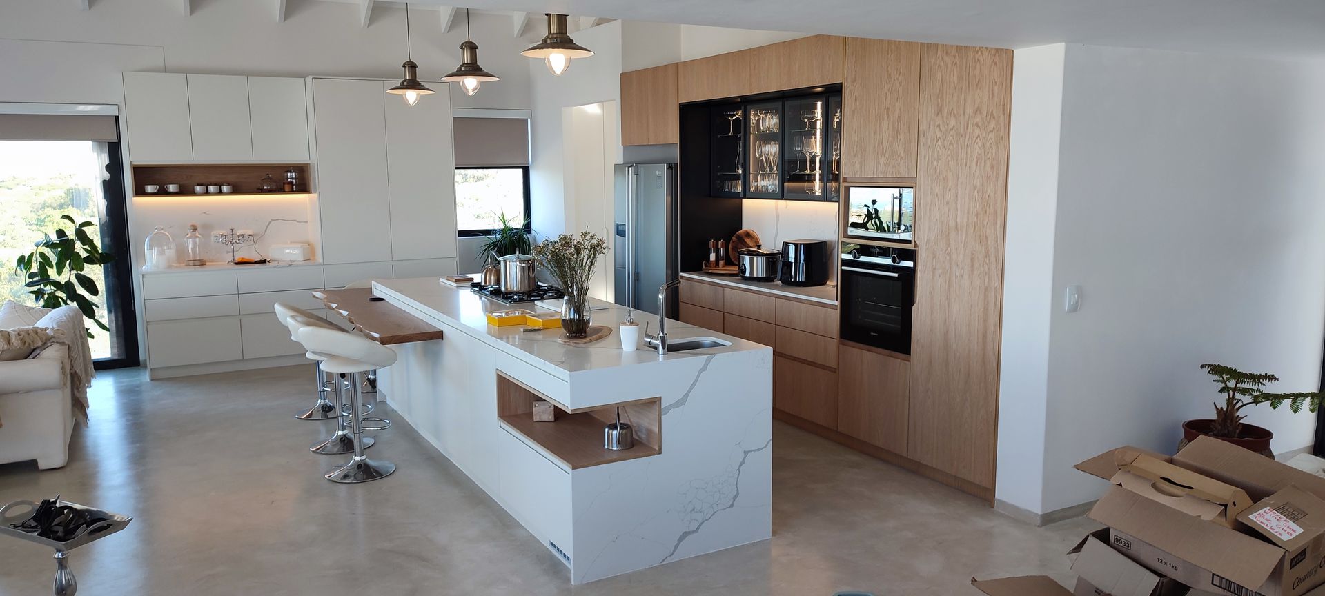A kitchen with white cabinets and wooden cabinets and a large island in the middle.