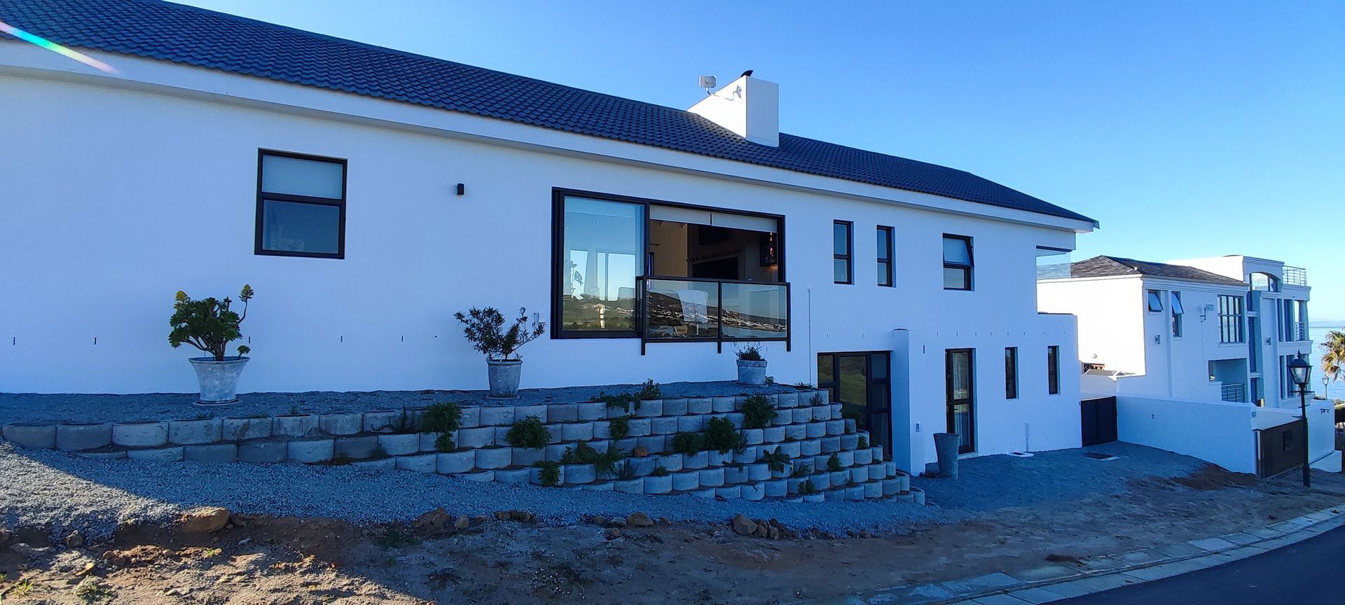 A white house with a blue roof is sitting on top of a hill.
