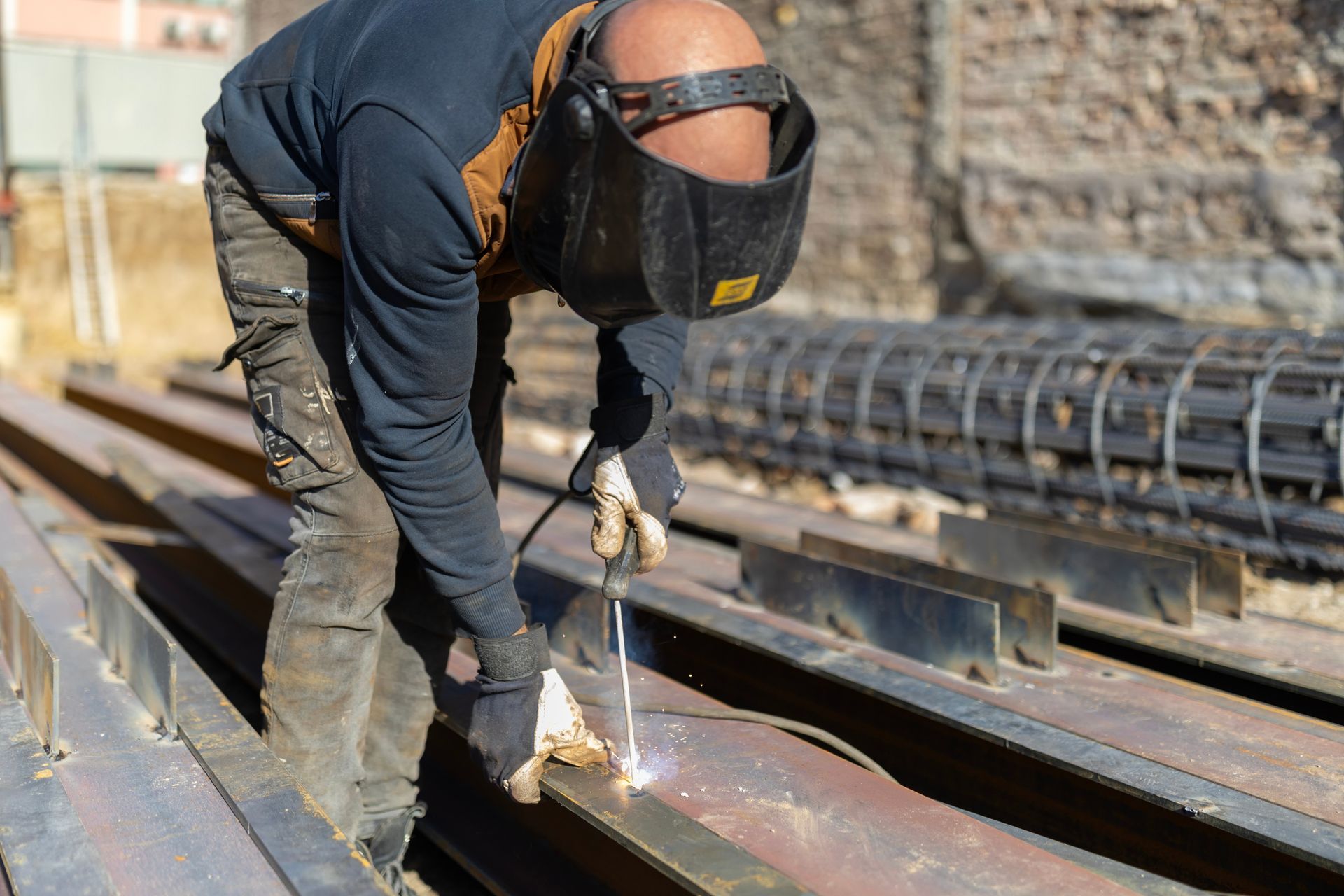 Foundation steel beam welding at a construction site with protective gear. Foundation steel beam welding at a construction site with protective gear.