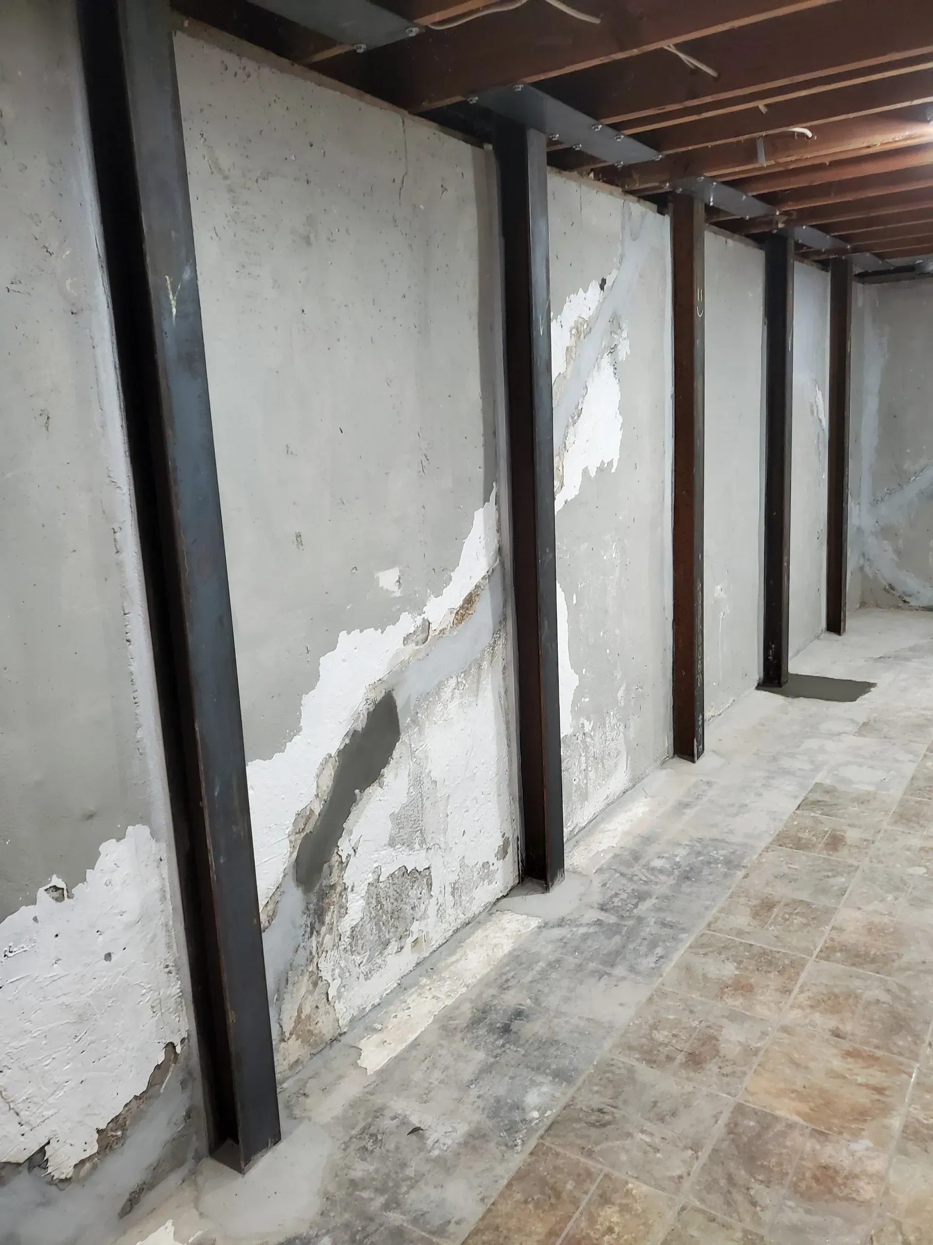 Metal beams installed along cracked foundation wall to provide structural reinforcement.
