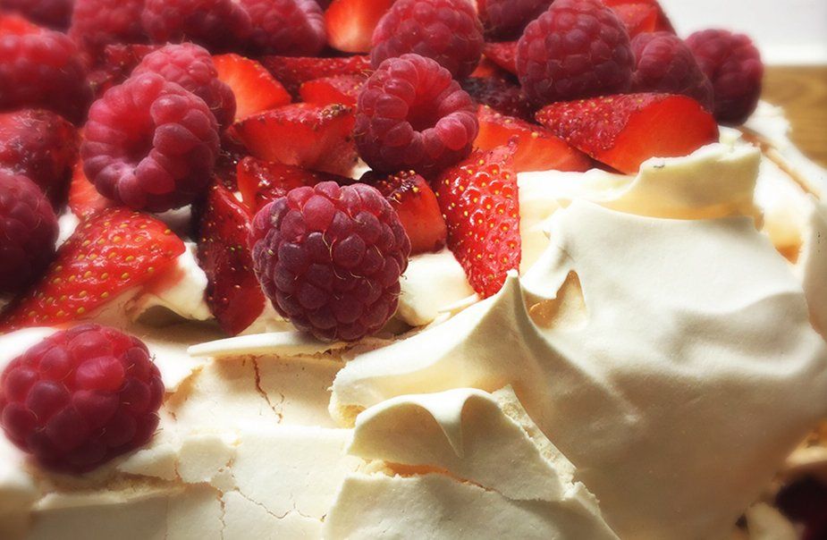 A close up of a dessert with raspberries and strawberries on top