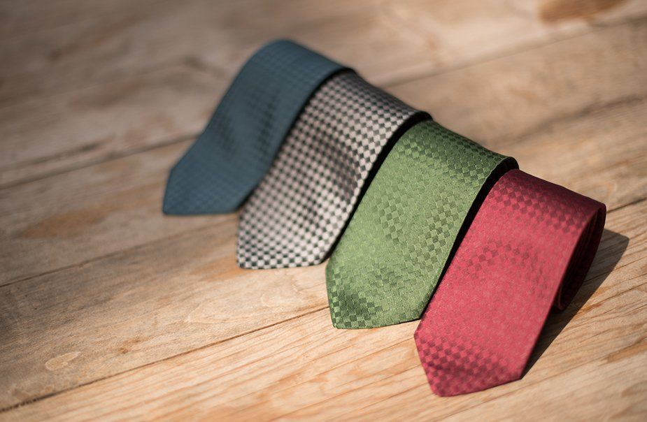 Three different colored ties are stacked on top of each other on a wooden table.