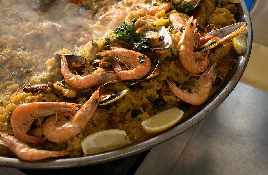 A pan of paella with shrimp mussels and lemon slices