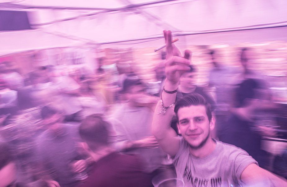 A man is taking a selfie in front of a crowd of people at a party.