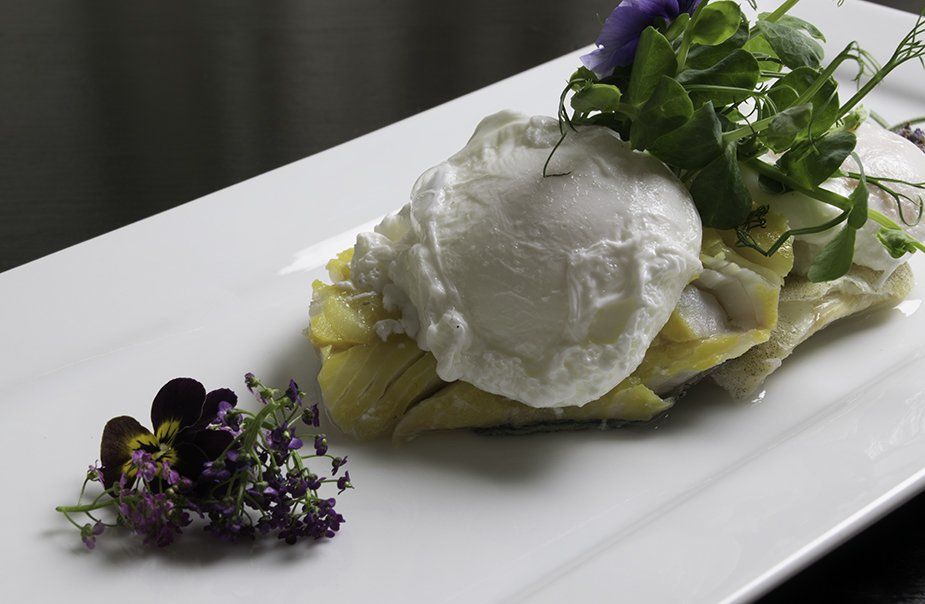 A white plate topped with a poached egg and flowers